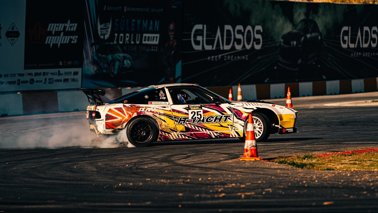 A vibrantly painted drift car skillfully maneuvers around cones on a sunny day.