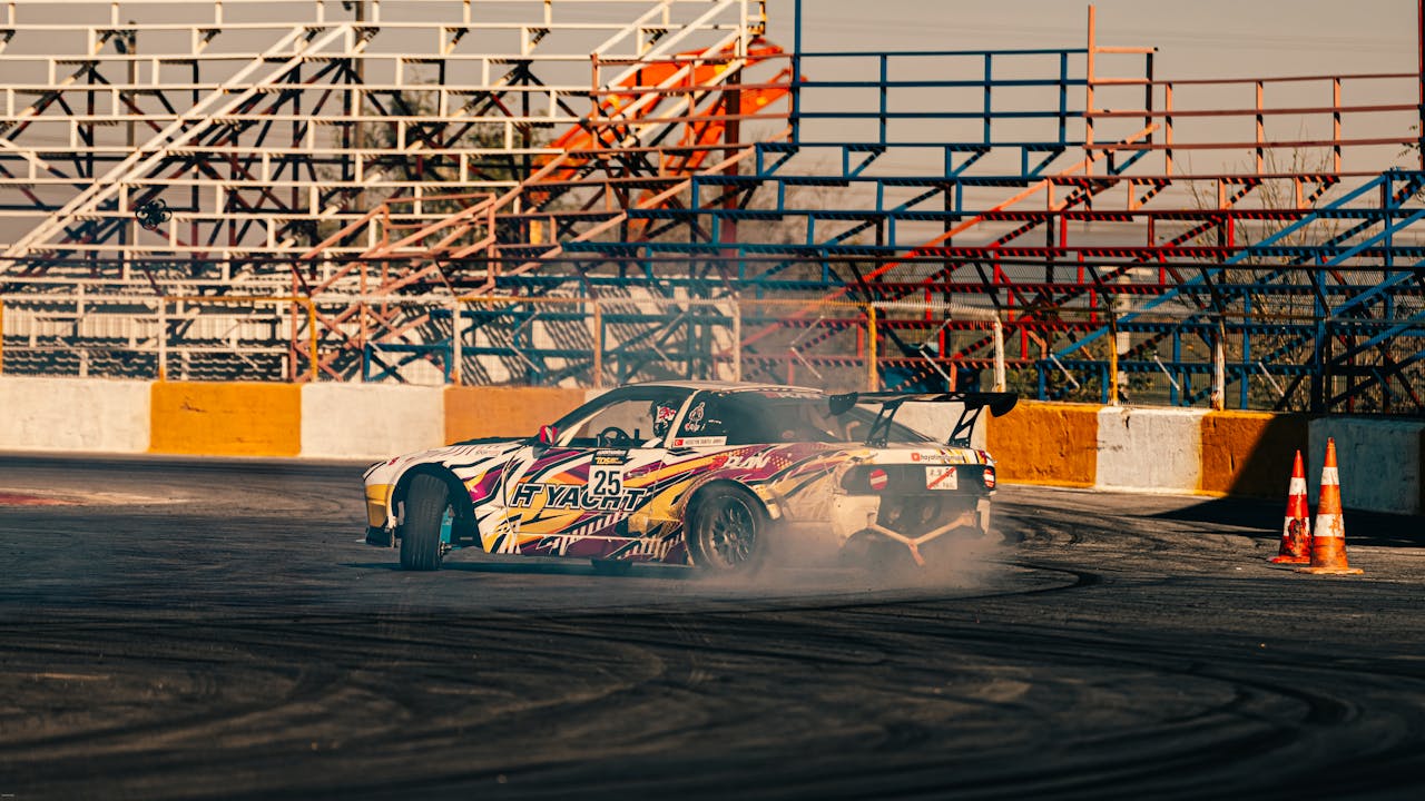 A colorful racing car drifts on a motorsport track with smoke and vibrant bleachers.